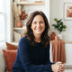 A friendly, smiling woman in a bright, modern home setting, representing a satisfied customer.